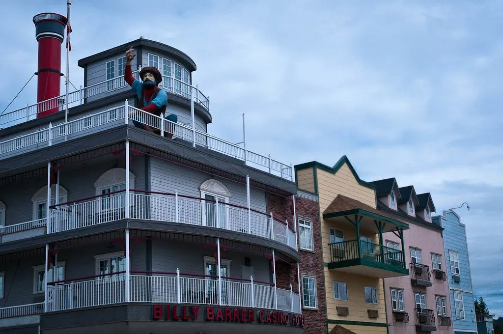 Billy Barker Casino Hotel in Quesnel: the sternwheeler-style corner with a red smokestack and a large prospector figure on the top deck, beside a row of colourful gabled facades — Billy Barker Casino Hotel