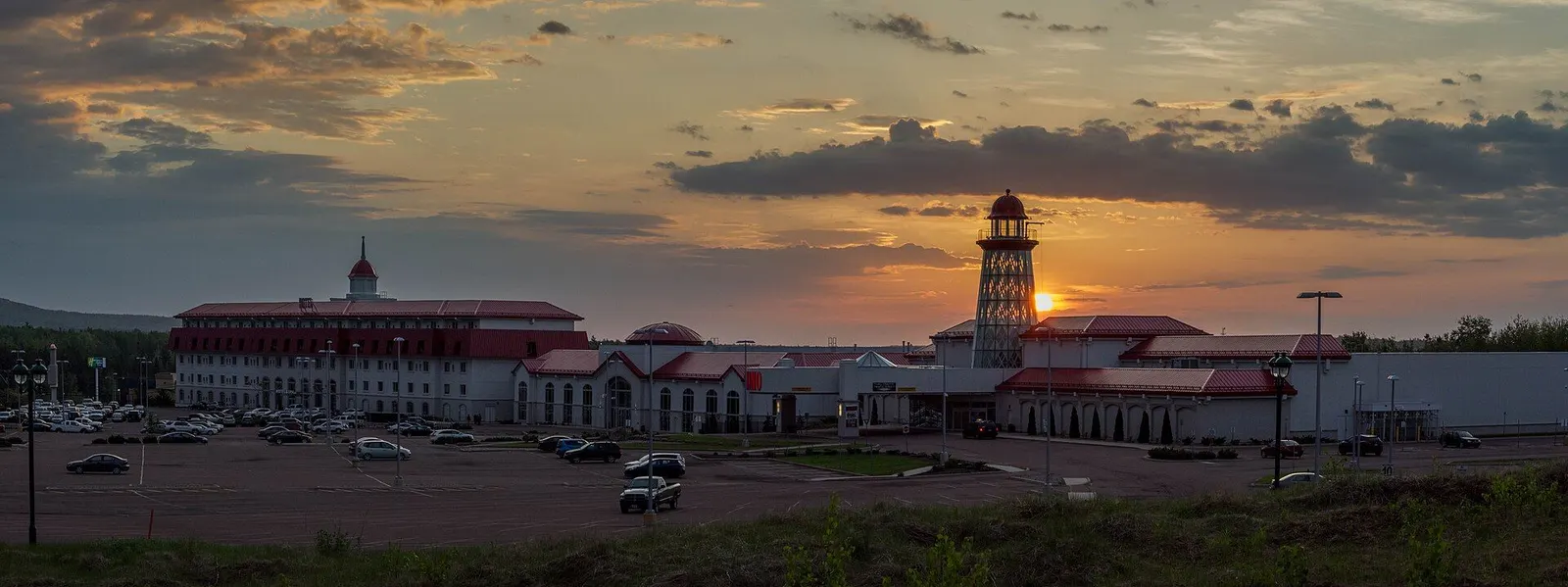 Casino New Brunswick in Moncton: the resort hotel with its red roofs and the landmark lighthouse tower, with the sun low on the horizon — Casino New Brunswick