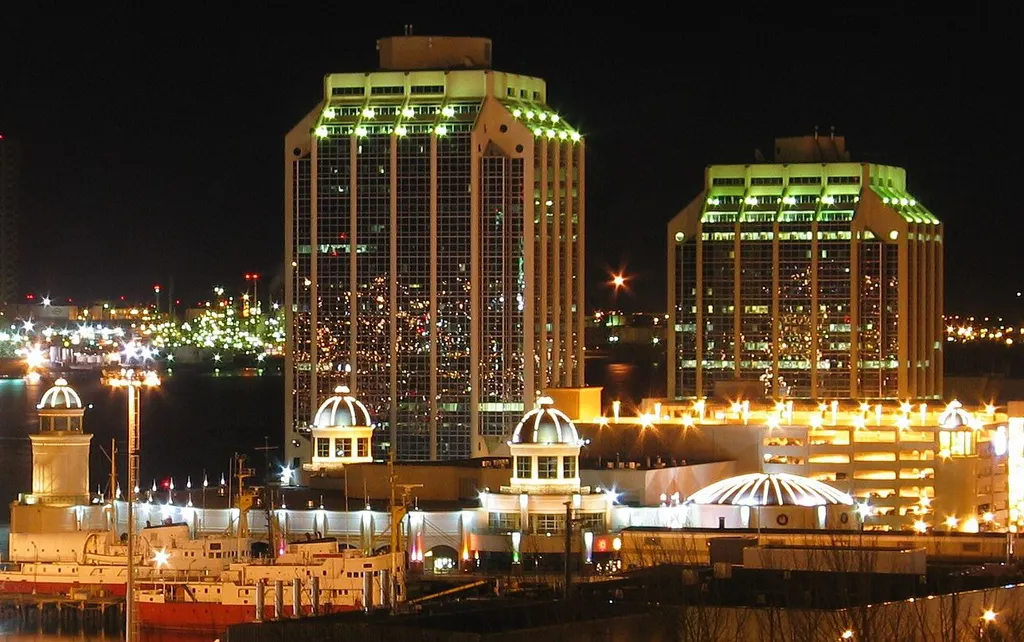 Casino Nova Scotia lit at night on the Halifax waterfront, its cupolas and domed rotunda above the pier with office towers behind. — Casino Nova Scotia Halifax