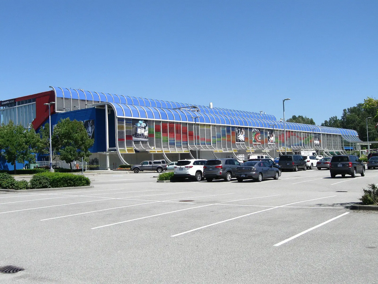 Elements Casino Surrey: the curved blue canopy running the full length of the facade, seen from the parking lot — Elements Casino Surrey