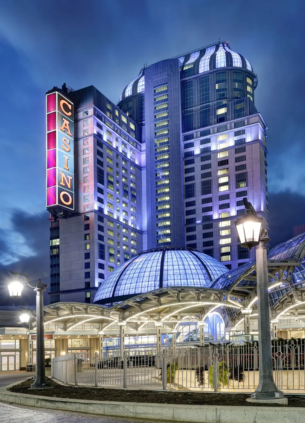 Fallsview Casino Resort in Niagara Falls at dawn: the lit hotel tower, the vertical CASINO sign and the glass dome behind the entrance canopy — Fallsview Casino Resort