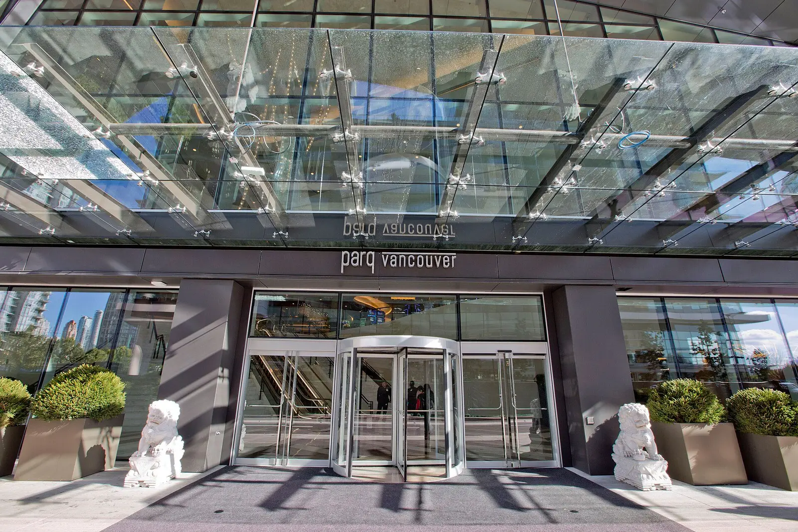 The main entrance to Parq Vancouver, with guardian lions flanking the revolving door — Parq Casino